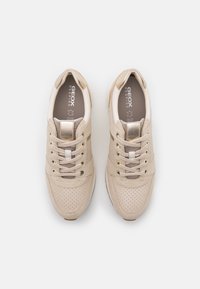Baskets en daim beige et mesh avec accents dorés et lacets, semelles intérieures estampillées « GEOX Respira », vues de dessus sur fond blanc.