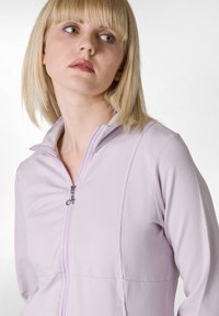 Ljus lavendelfärgad zip-up jacka gjord av mjukt material, med ståkrage och en silverdragkedja. Slät textur med subtila sömnadsdetaljer.