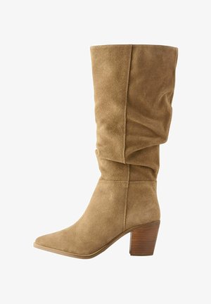 Rudi suediniai kelio ilgio batai su švelniu dizainu, smailiu pirštu ir mediniu pakulnė. Minkšta tekstūra su matomais siuvimo akcentais.