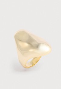 Gładki, wypolerowany złoty pierścionek z abstrakcyjną, bulwiastą, nieregularnie ukształtowaną górną powierzchnią na jednolitym tle.