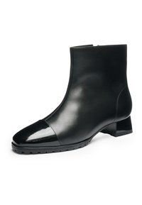 Bottine en cuir noir avec embout brillant, talon bas carré, fermeture éclair latérale et semelle en caoutchouc texturée.