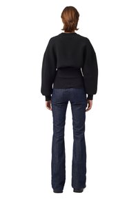 Černá, oversized mikina s žebrovanými okraji a balónovými rukávy, doplněná tmavě modrými rozšířenými džínami. Hladké látky s minimálními detaily.