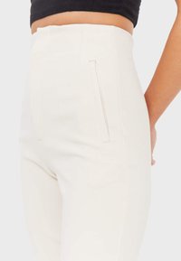 Hoge taille, aansluitende witte broek met een gladde textuur en zijzakken met rits. Minimalistisch ontwerp met strakke lijnen en een op maat gesneden silhouet.
