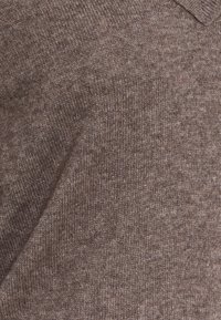 Pull tricoté marron, présentant un tissu texturé avec un motif chiné subtil, un col en V et un col côtelé.