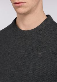Maglione grigio scuro a maglia con scollatura rotonda, tessuto testurizzato e un sottile dettaglio del logo sul petto.