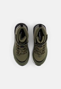 Zielone buty sportowe z gładką cholewką z materiału, wzmocnioną częścią palców, czarnymi akcentami i białą podeszwą. Sznurowadła są zintegrowane z oczkami.