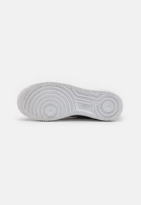 Nike sportska tenisica s potplatom od bijele gume, koja sadrži kružni uzorak gaznog sloja i uzdignute rubove za bolju prilagodljivost. Glatka površina s utisnutim logotipom.