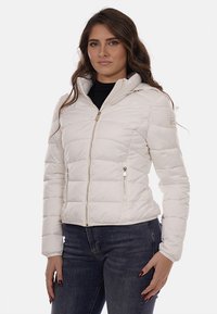 Giacca imbottita bianca con zip frontale, cappuccio e due tasche laterali con zip. Presenta un design trapuntato, una texture liscia e polsini elasticizzati.