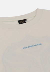 Beige katoenen t-shirt met blauwe "TOMORROWLAND" tekst. Gladde textuur met een ronde halslijn en subtiele grafische ontwerpen.