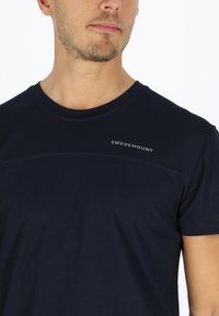 T-shirt blu navy con maniche corte, scollatura rotonda, tessuto testurizzato e logo a contrasto "SWEDEMOUNT" sul petto.