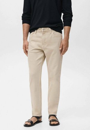 Chinos beiges en coton avec une coupe standard, dotés d'une fermeture éclair, de cinq poches et d'une texture lisse. Assortis à des sandales noires.