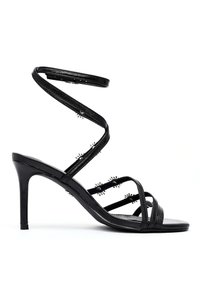 Sandales à talons hauts noires avec de fines lanières entrecroisées. Cuir verni lisse, enroulement spiralé autour de la cheville et clous décoratifs le long des lanières.