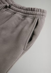 Grå sweatpants med elastisk talje, sidelommer, glat tekstur og et blødt, afslappet design. Sømdetaljer langs sømmene.