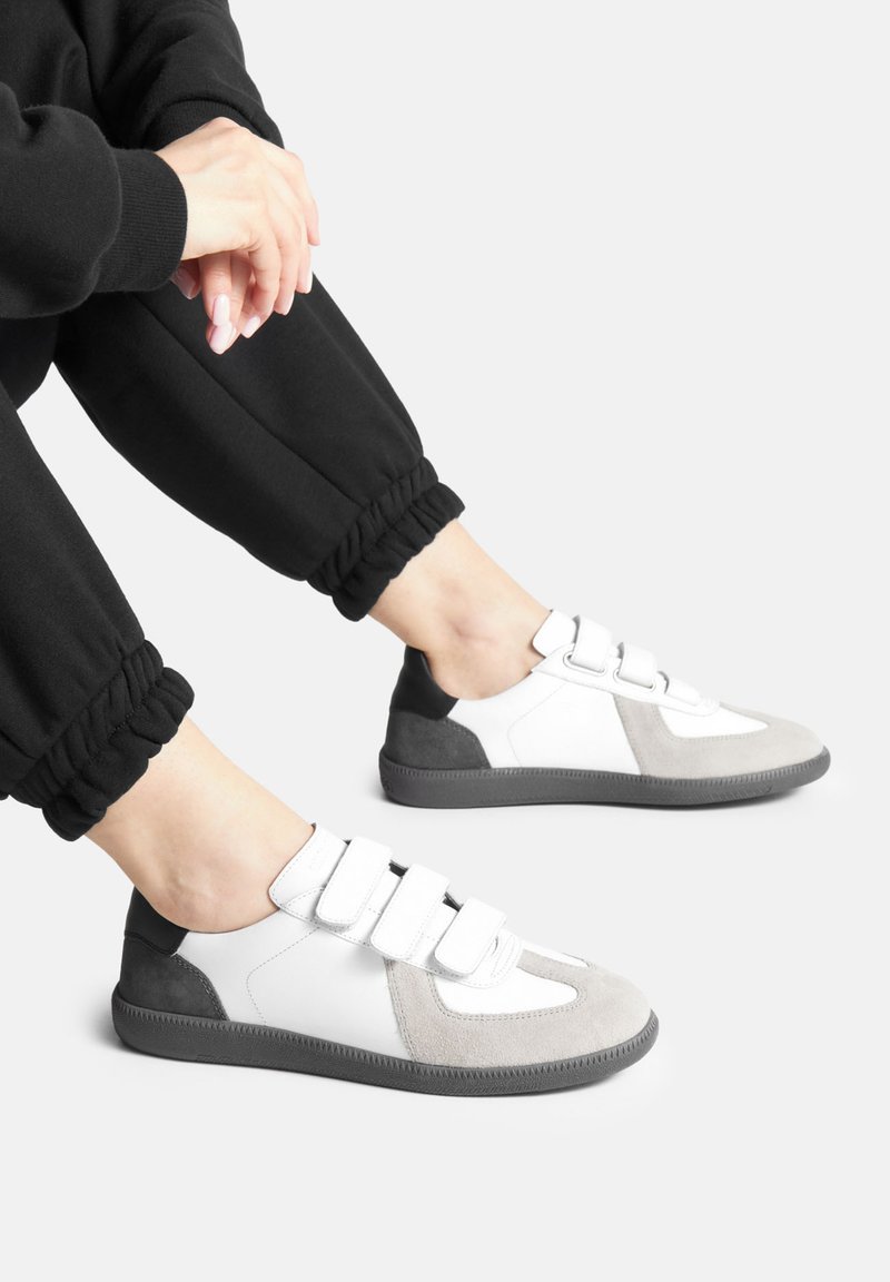 Valge, halli ja musta värvi Velcro tossud, millel on sametised ja siledad paneelid. Omab ümmargust varbaosa ja tekstureeritud kummist tallat.