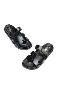 Sandales à glissière noires avec deux larges brides présentant des découpes, une semelle intérieure texturée et une semelle extérieure lisse. Logo doré sur la semelle intérieure.