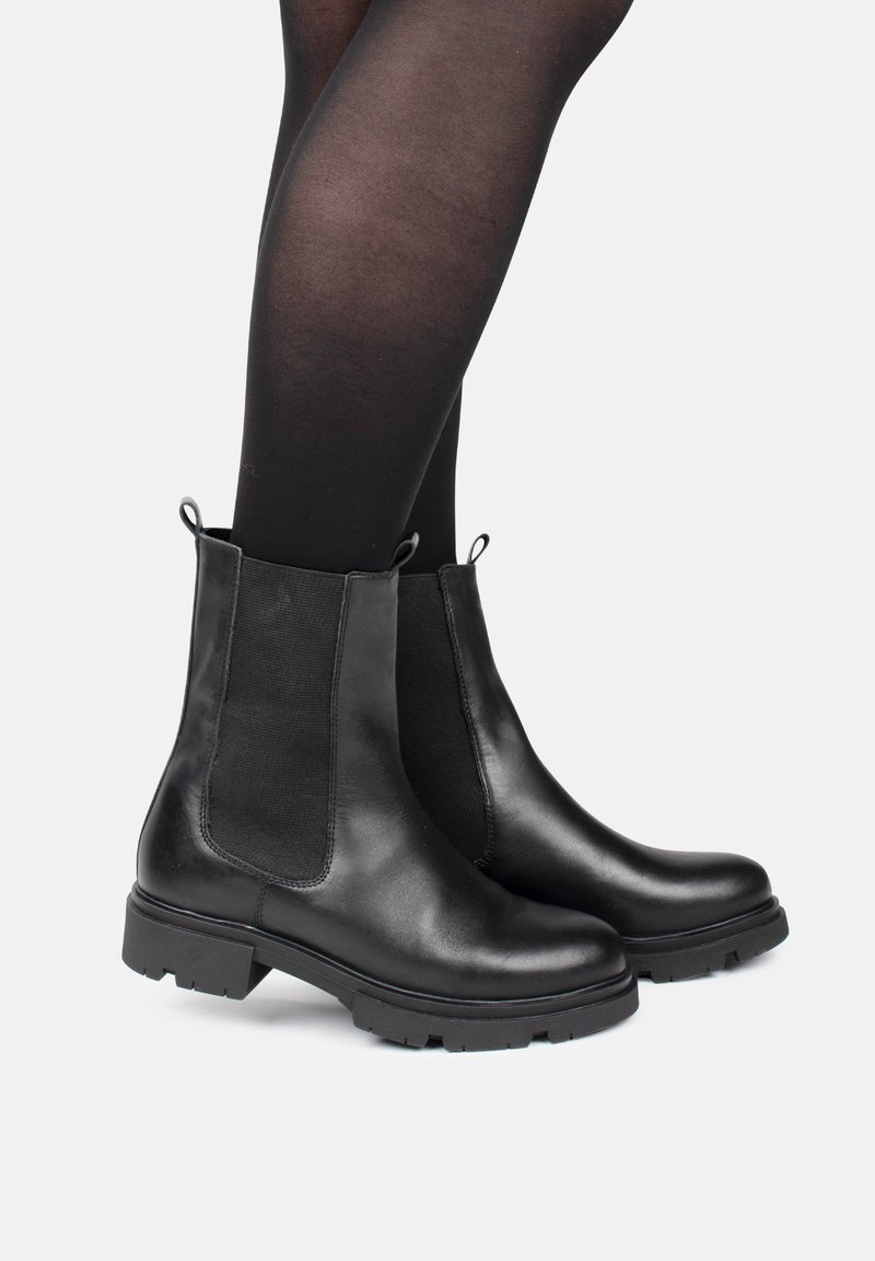 Botas de tobillo de cuero negro con paneles elásticos laterales, puntera redonda y suela resistente. Cuenta con bucles para facilitar su colocación.