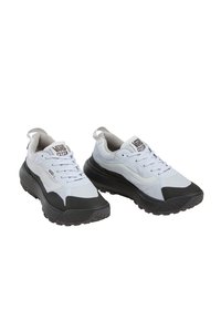 Un paio di scarpe Vans MTE bianche e nere con suole nere spesse e lacci bianchi, angolate leggermente a destra su uno sfondo bianco.