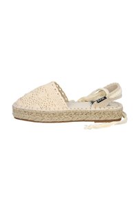 Espadrille de color crema con parte superior de ganchillo, suela de yute y cintas ajustables en el tobillo. Presenta una textura tejida y un perfil plano.