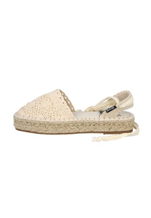 Espadrille de color crema con parte superior de ganchillo, suela de yute y cintas ajustables en el tobillo. Presenta una textura tejida y un perfil plano.