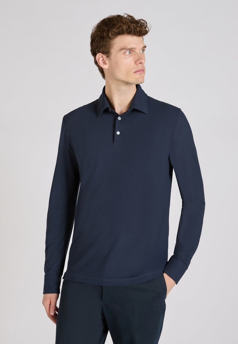 Marineblauw poloshirt met lange mouwen, een kraag, drie knopen en een rechte zoom. Gemaakt van een gladde stof met een subtiele textuur.