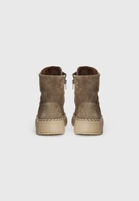 Bottines en daim marron avec une finition texturée, dotées d'une fermeture éclair et d'une semelle beige surélevée avec des accents tressés. Vue arrière.