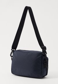 Navy nylon crossbody bag with a flat rectangular shape, adjustable black strap, and subtle textured pattern on the surface.