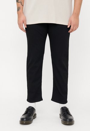 Zwarte denim broek met een rechte snit, voorzien van een schone zoom. Gepaarde met stevige zwarte leren schoenen en witte sokken.