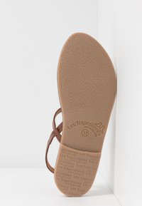 Suela de sandalia de cuero marrón con un patrón texturizado, con un sello de la marca y la talla 37 embellecidos en el diseño.