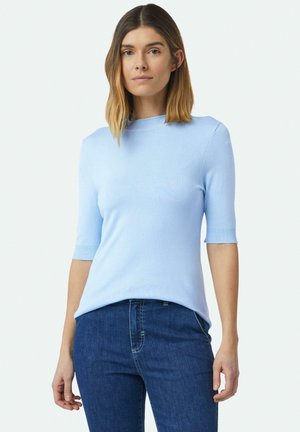 Lichtblauw T-shirt met korte mouwen in een zachte gebreide stof, met een neklijn en ribgebreide manchetten, gecombineerd met donkere spijkerbroeken.