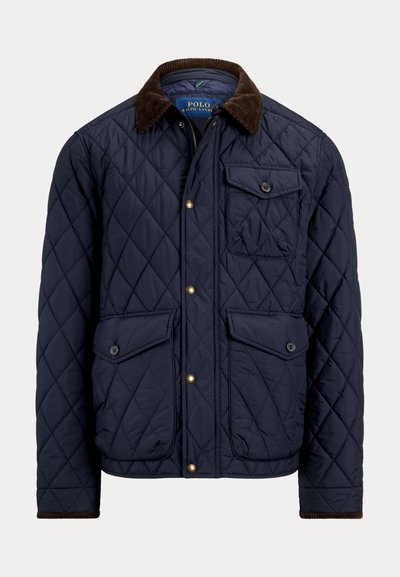 Veste matelassée bleu marine avec col en velours côtelé marron, fermeture éclair et boutons sur le devant, deux poches à rabat boutonnées et une poche poitrine avec bouton.
