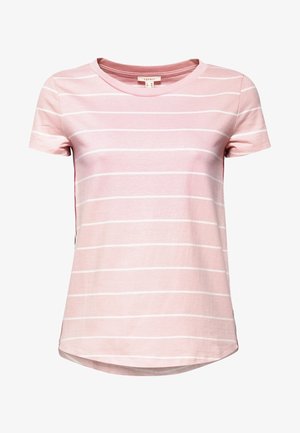 Kvinde iført en lyserød t-shirt med korte ærmer og striber, højtaljede mørke jeans med vide ben og knapper foran samt hvide sneakers, stående på grå baggrund.