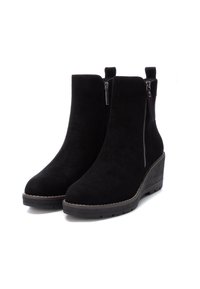 Botas negras hasta el tobillo de ante, con tacón de cuña, cierre de cremallera lateral y un detalle de costura mínima a lo largo de la suela.