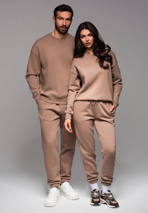 Hellbraune, passende Sweatshirts und Sweatpants mit einem lockeren Schnitt, gerippten Bündchen und Kordelzugbund. Sneakers runden das Outfit ab.