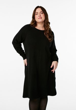 Black knit dress with long sleeves, round neckline, and a relaxed silhouette. Features a textured finish and below-the-knee length.