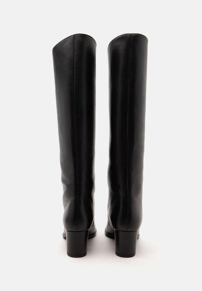 Paire de bottes hautes en cuir noir avec talons blocs, vues de dos sur un fond blanc uni.