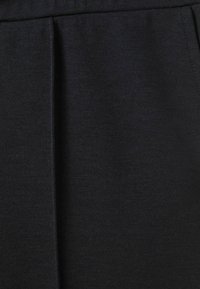 Material negru cu o textură netedă și un luciu subtil, având un design cu pliuri frontale și un stil minimalist.