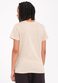T-shirt in cotone beige con maniche corte, scollatura rotonda e vestibilità comoda. Tessuto liscio, senza motivi o accessori visibili.