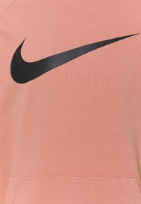 Sweatshirt Nike en tissu corail doux avec un grand logo swoosh noir, texture côtelée et poche kangourou devant.
