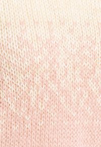 Dzianina o gradientowych odcieniach miękkiego różu i kremu. Charakteryzuje się teksturowanym wzorem z wplecionymi ściegami.