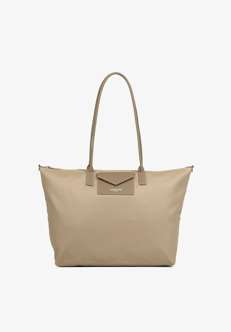 Sac cabas beige avec longues anses et une poche à rabat à l'avant portant l'inscription "Lancaster Paris" sur fond blanc.