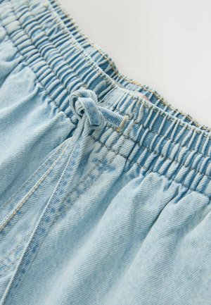 Svetlomodré rifľové nohavice s nariaseným elastickým pásom a viazaným šnúrkou vpredu, zobrazujúce podrobné prešitie a textúru látky.