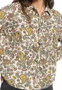 Knapp-up skjorta i ljus grädde med ett blommönster och paisleymönster i gult, rosa och grönt, med en texturerad tyg och krage.