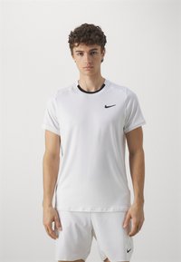 Hvit treningstrøye laget av glatt stoff, med korte ermer, svart rund hals, og en liten svart Nike-logo på brystet.