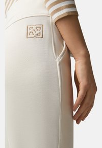 Lichtbeige sweatpants met een zachte textuur, voorzien van gestikte naden en een geborduurd logo op de zijzak.
