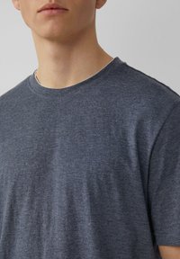 Baumwoll-T-Shirt in Dunkelblau mit Rundhalsausschnitt, kurzen Ärmeln und einer glatten, leicht strukturierten Oberfläche. Keine sichtbaren Muster oder Akzente.