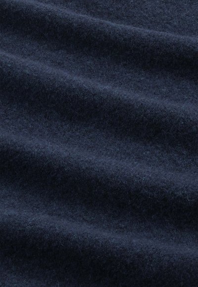 Tummansininen villakangas, jossa on pehmeä, teksturoitu pinta, joka esittää hienovaraisia aaltoja ja tiheää, lämmintä ulkonäköä, mikä tekee siitä ihanteellisen vaatteisiin tai asusteisiin.