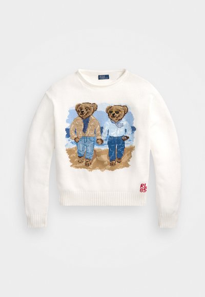 Suéter blanco de punto con dos osos ilustrados en ropa casual, con patrones detallados y fondo azul claro. Logo rojo en el dobladillo.