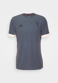 Maillot de football Juventus gris foncé avec trois étoiles au-dessus du logo, logo Adidas sur la poitrine et détails rose clair aux poignets et au col.