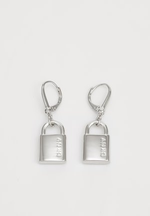 Brincos de metal prateado em forma de cadeados com um acabado polido, apresentando um fecho de mola e uma marca gravada na parte da frente.