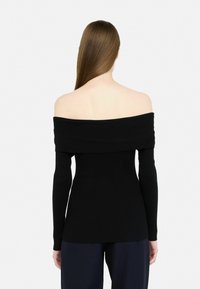 Top nero a spalle scoperte in tessuto a coste con maniche lunghe. Il materiale appare testurizzato, silhouette aderente e cuciture piatte al colletto.